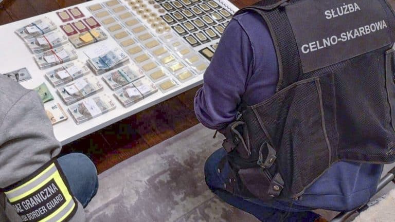 Na zdjęciu widoczny jest funkcjonariusz służb celno-skarbowych przy stole z pieniędzmi i innymi przedmiotami.