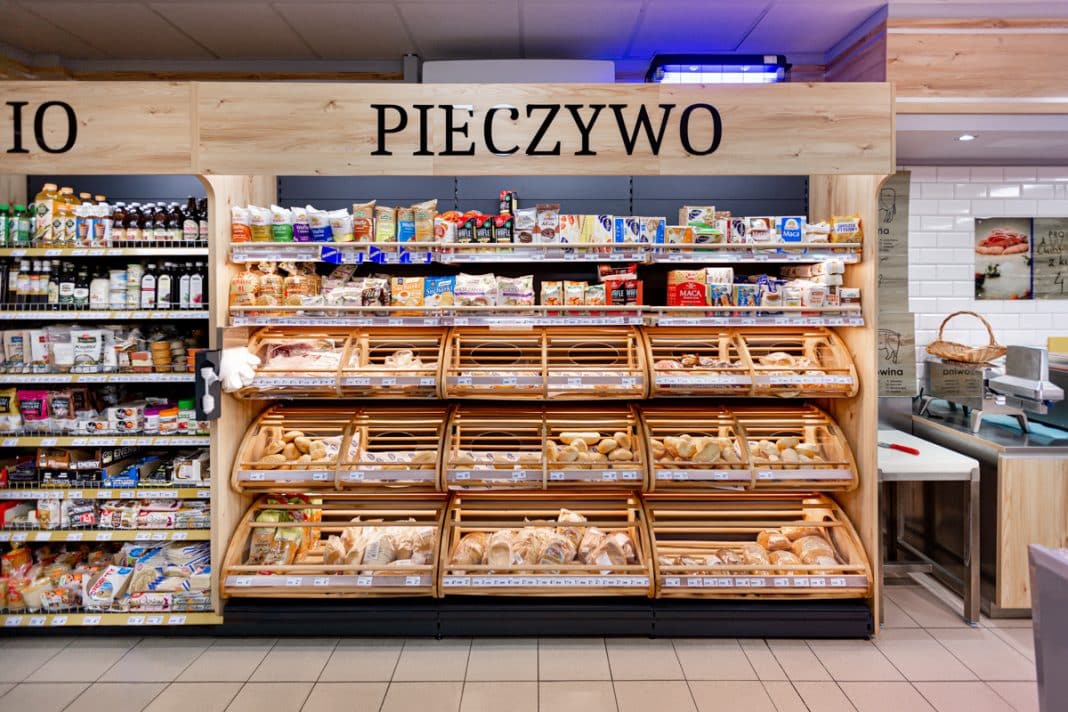 Sekcja pieczywa w sklepie spożywczym z r&oacute;żnymi rodzajami chleba i bułek na p&oacute;łkach.