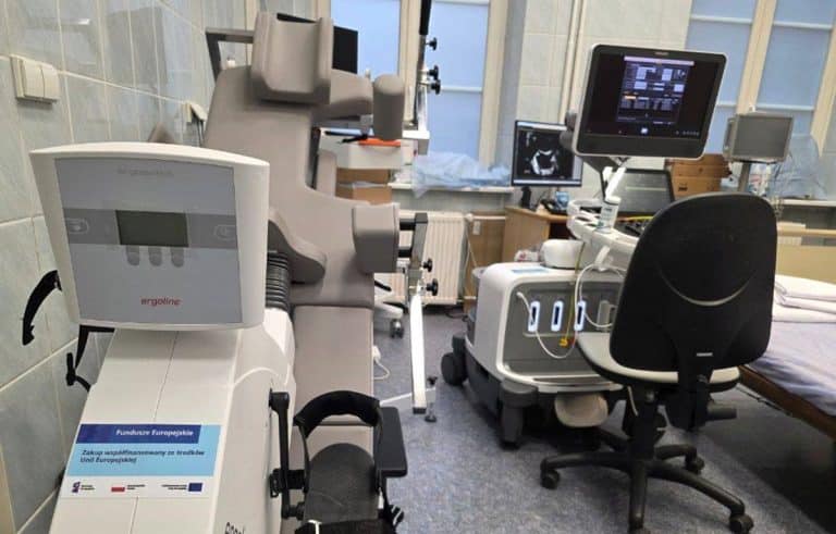 Nowoczesny sprzęt diagnostyczny w olsztyńskim szpitalu, w tle komputery i ł&oacute;żko pacjenta.