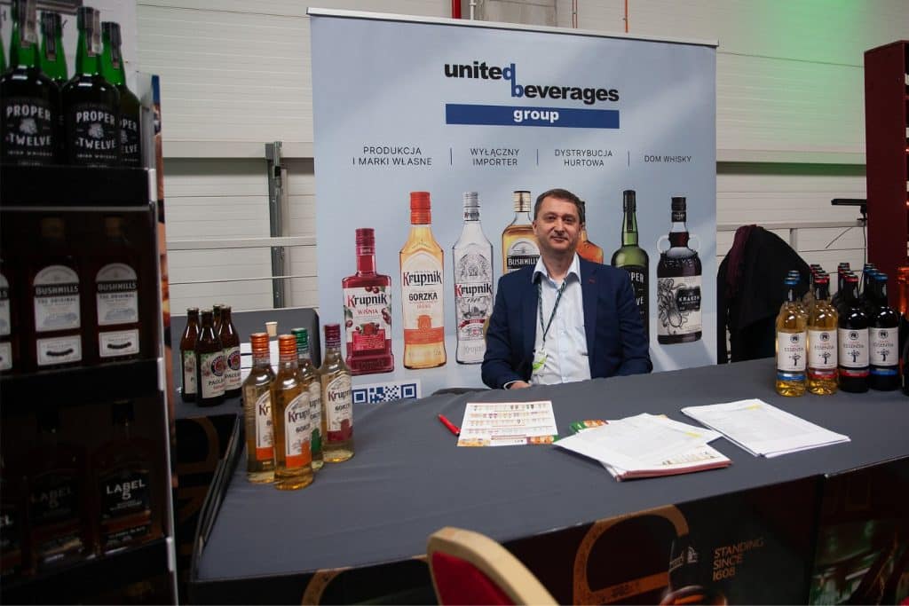 Stoisko z alkoholami i producentem na targach w Gdańsku, w tle plansza z logo grupy United Beverages.