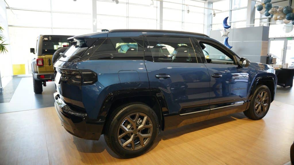 Nowy Jeep Compass w salonie samochodowym, widoczny z boku i z tyłu, w nowoczesnym wnętrzu.