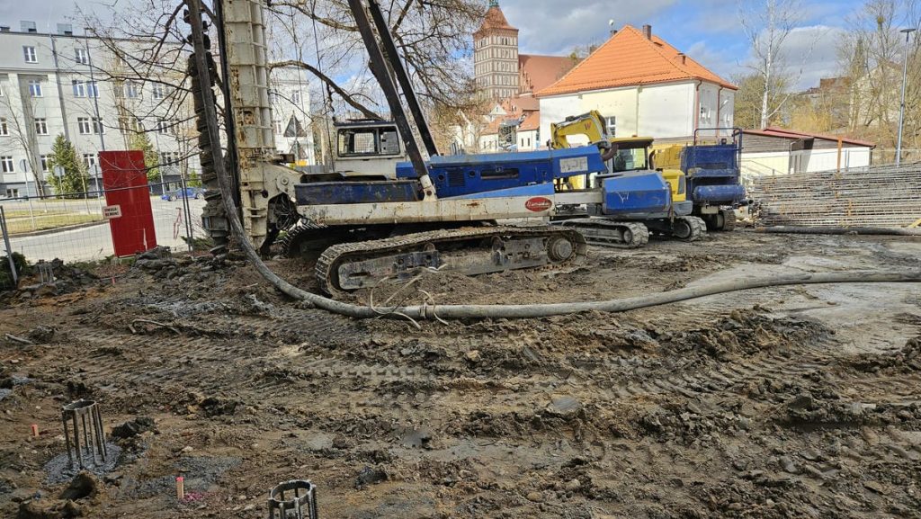 Budowa nowego obiektu usługowego w centrum Olsztyna, widoczne wykopy i maszyny budowlane.