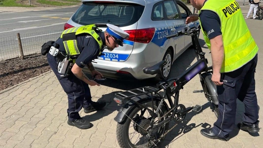 Policjanci sprawdzają rower elektryczny po wypadku z udziałem dziecka i samochodu na drodze.