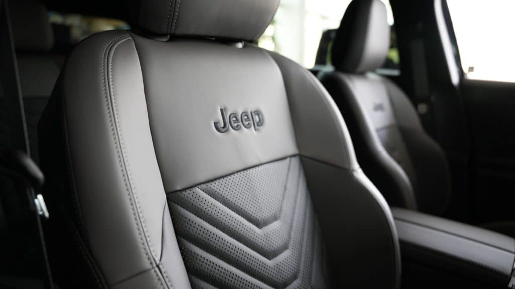 Wnętrze nowego Jeepa Compassa z wyraźnym logo marki na fotelu kierowcy, w jasnej tapicerce.