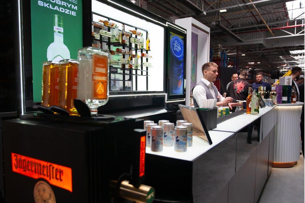 Stoiska z alkoholem i napojami na targach w Gdańsku, uczestnicy rozmawiają i prezentują produkty.