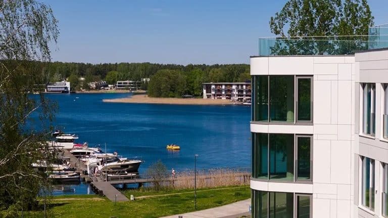 Widok na jezioro Ukiel z nowoczesnego budynku nad brzegiem, w tle łodzie i zieleń.