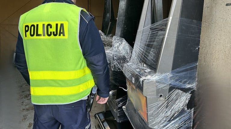 Policjant przy uszkodzonym automacie do gier, zabezpieczony folią stretch.