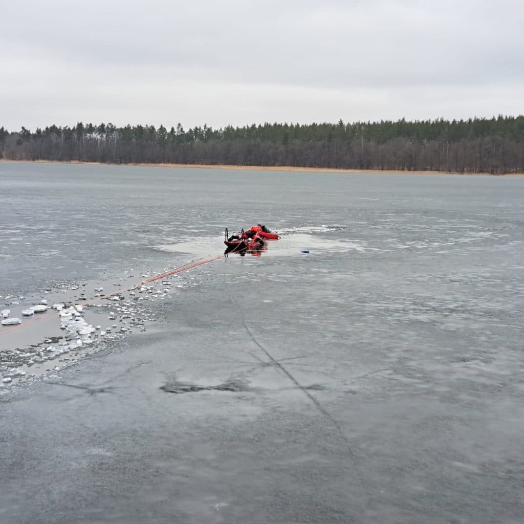 L&oacute;d załamał się na jeziorze, na powierzchni widać rozbity l&oacute;d i ratunkowe wyposażenie.