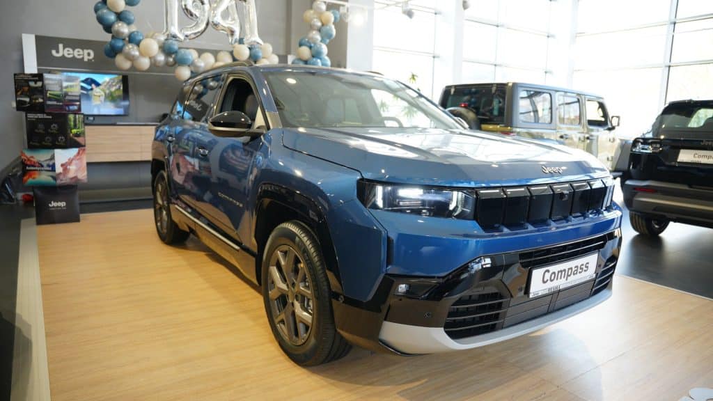Nowy Jeep Compass na wystawie w salonie samochodowym, w tle inne modele marki.