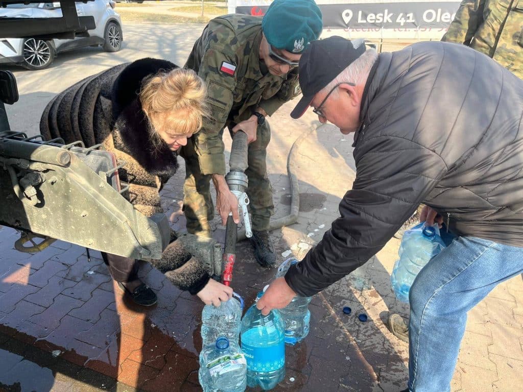 Wojsko i mieszkańcy napełniają butelki wodą w miejscu akcji ratunkowej.
