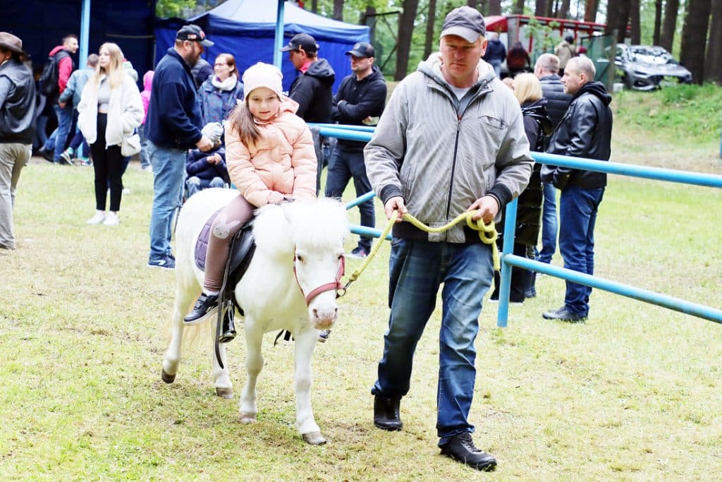 Dziecko na koniu podczas targ&oacute;w ogrodniczych w Olsztynie, wok&oacute;ł tłum uczestnik&oacute;w i stoiska.