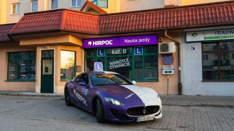 Nowy punkt szkoły nauki jazdy Hirpol na Jarotach, samoch&oacute;d z oznaczeniem L przed wejściem.