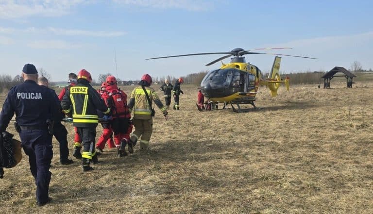 Służby ratunkowe na polu przy jeziorze Linowo, helikopter w tle, akcja ratunkowa na miejscu.