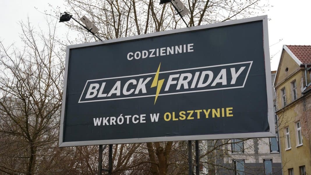 Billboard w Olsztynie z napisem 'Codziennie Black Friday' i 'Wkr&oacute;tce w Olsztynie', na tle drzew i budynk&oacute;w.