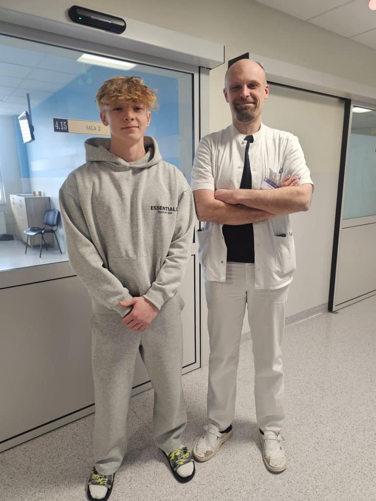 Lekarz i młody pacjent stojący w szpitalu, przygotowani do operacji ortopedycznej.