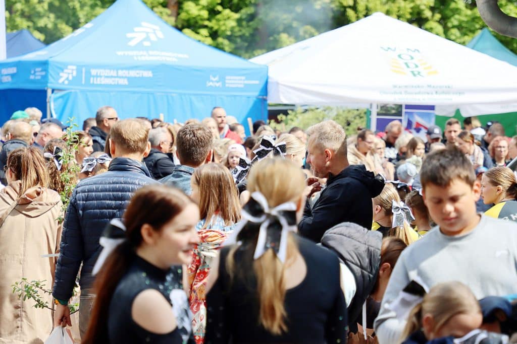 Tłum ludzi na targach ogrodniczych w Olsztynie, stoiska i namioty w tle.