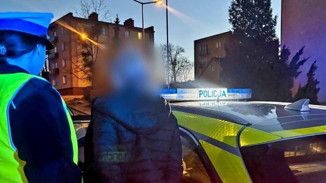 Kobieta po kolizji z ogrodzeniem, policjant stoi obok na miejscu zdarzenia, wieczorem.