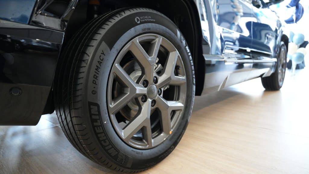 Zdjęcie nowego Jeepa Compassa na wystawie, ukazujące koło i część nadwozia, w tle balony i jasne światło.