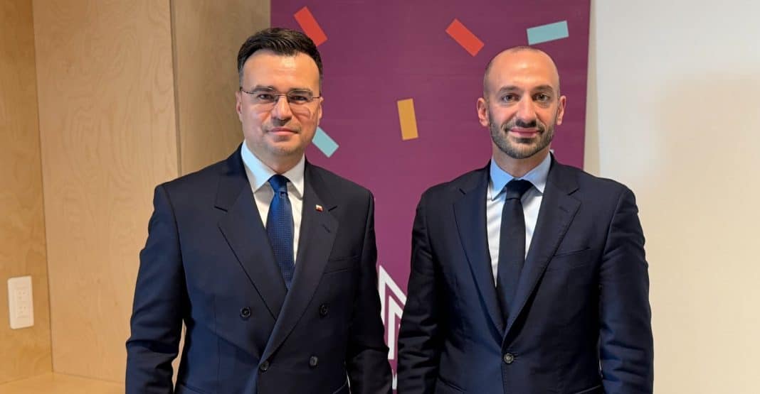 Dw&oacute;ch mężczyzn w garniturach na tle r&oacute;żowego tła z kolorowymi kształtami.