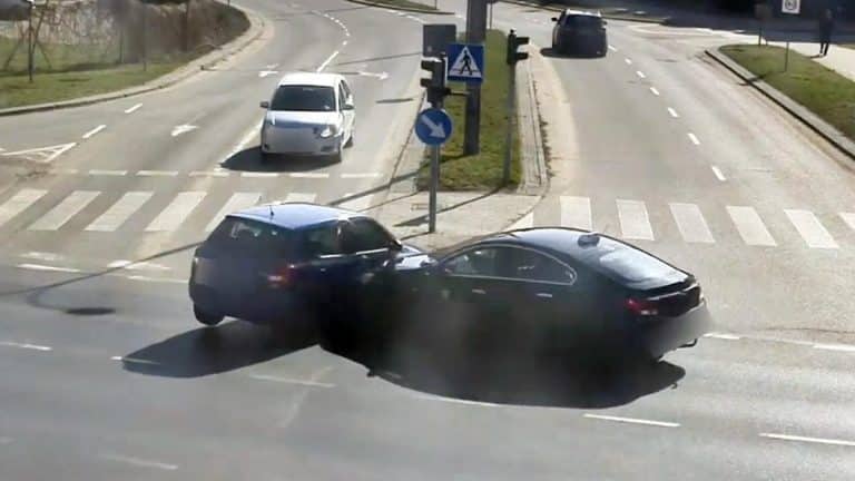 Zderzenie dw&oacute;ch samochod&oacute;w na skrzyżowaniu w Olsztynie, w tle znaki drogowe i przejście dla pieszych.