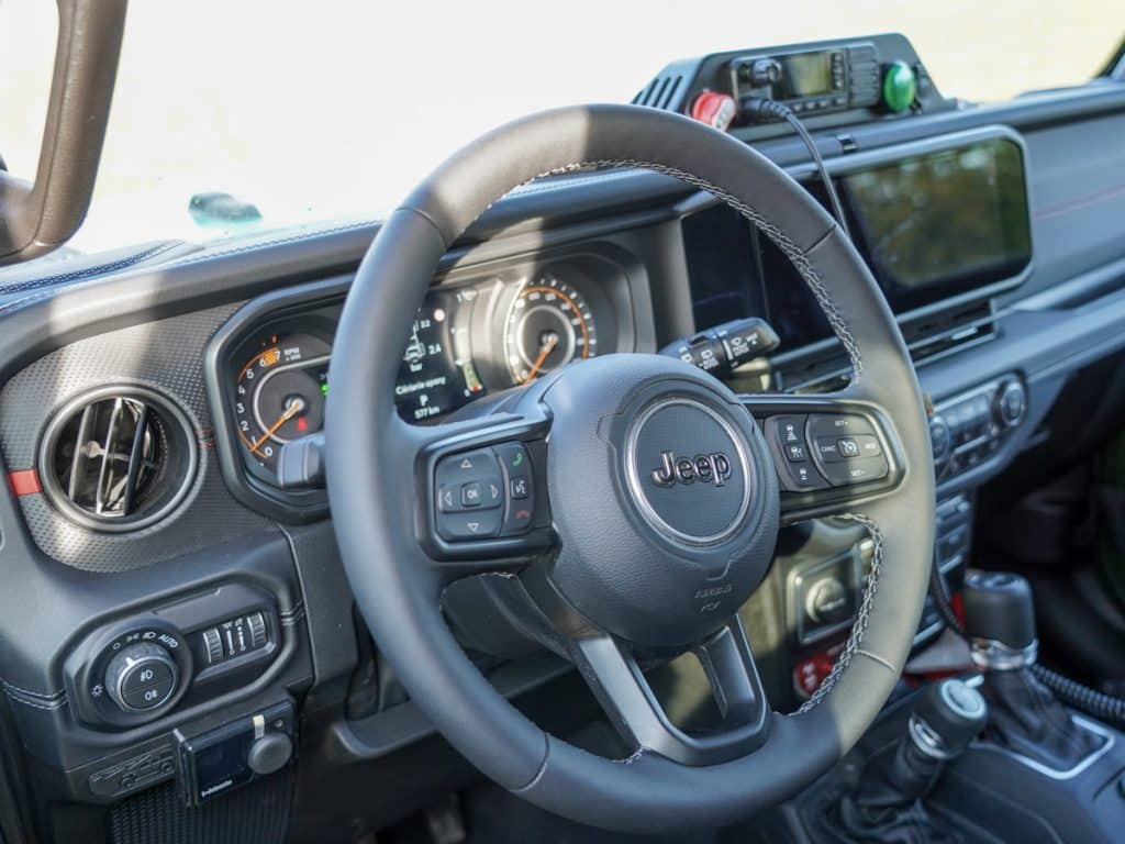 Wnętrze nowoczesnego samochodu patrolowego Jeep, widoczny kierownica i deska rozdzielcza.