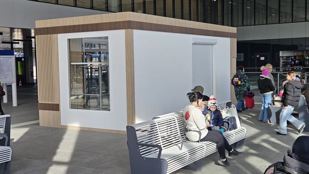 Nowa wyspa handlowa w holu dworca Olsztyn Gł&oacute;wny, wok&oacute;ł pasażerowie i oczekujący na pociąg.