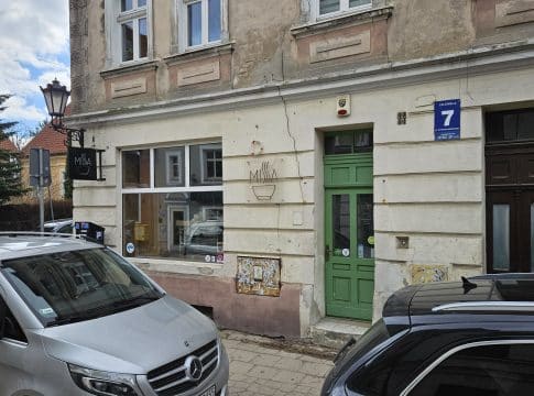 Widok na zamknięty lokal przy ul. Lelewela na olsztyńskiej Star&oacute;wce, z samochodami na pierwszym planie.