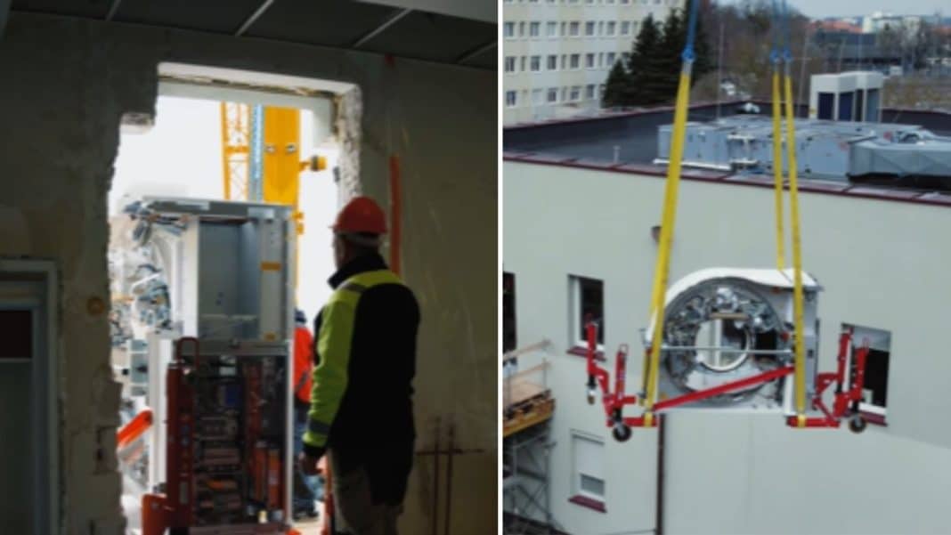 Pracownicy instalują nowoczesne urządzenie diagnostyczne przez wybite okno w szpitalu.