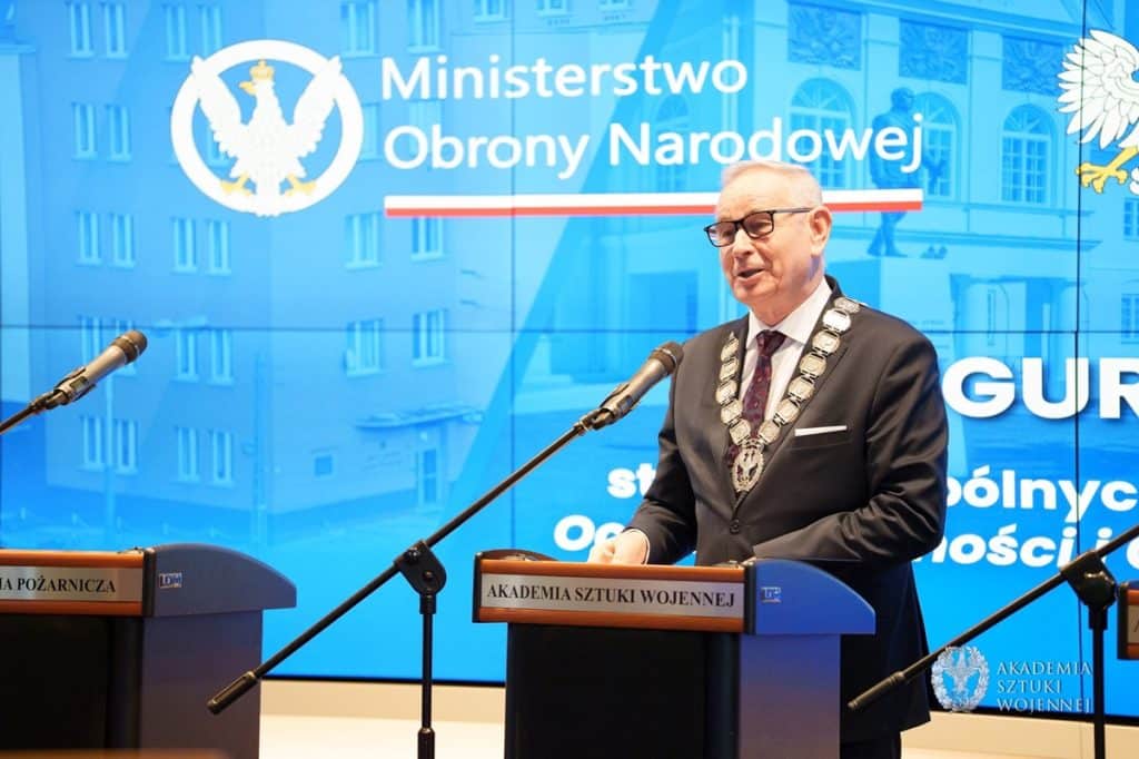 Mężczyzna w garniturze i medalach przemawia podczas konferencji przed logo Ministerstwa Obrony Narodowej.