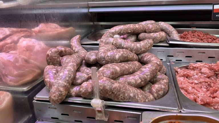 Biała kiełbasa na stoisku mięsny w sklepie Intermarch&eacute; Olsztyn, obok inne mięsa i wyroby.