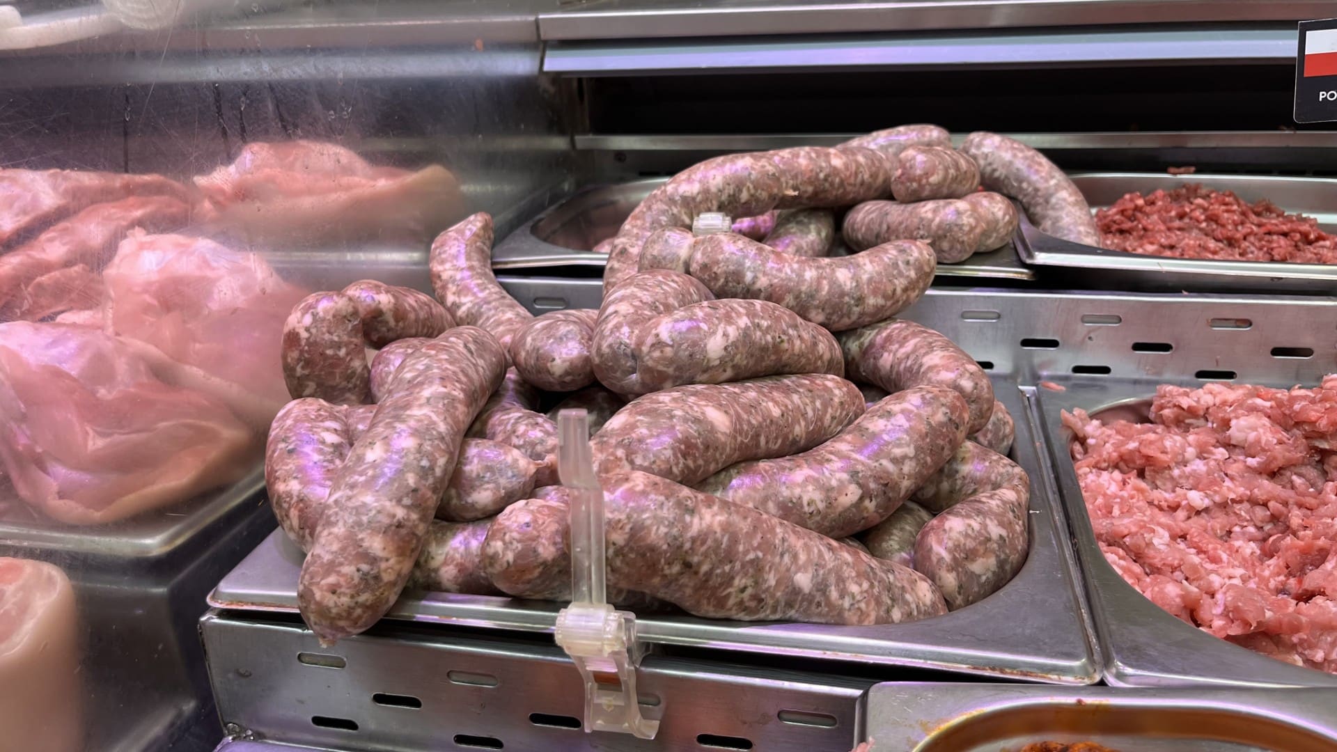 Biała kiełbasa na stoisku mięsny w sklepie Intermarch&eacute; Olsztyn, obok inne mięsa i wyroby.