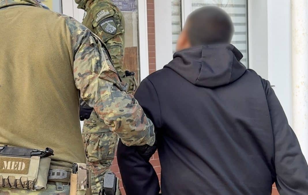 Funkcjonariusze Straży Granicznej i policji podczas akcji na ulicy, zatrzymują podejrzanego mężczyznę.