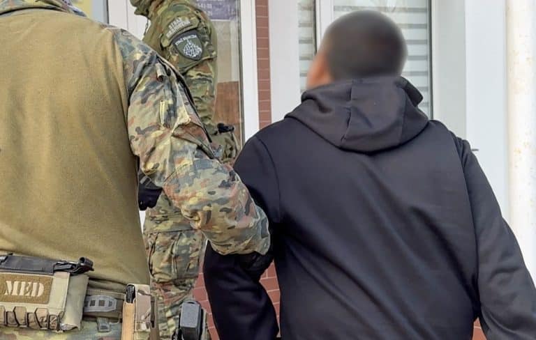 Funkcjonariusze Straży Granicznej i policji podczas akcji na ulicy, zatrzymują podejrzanego mężczyznę.