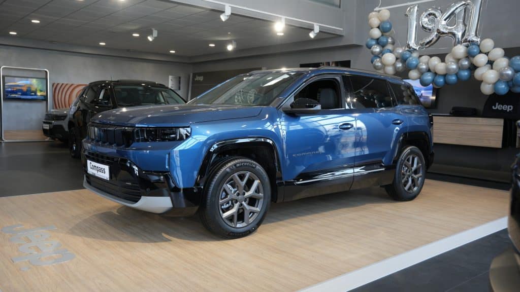 Nowy Jeep Compass na wystawie w salonie samochodowym, w kolorze niebieskim, z nowoczesnym designem i dużym prześwitem.
