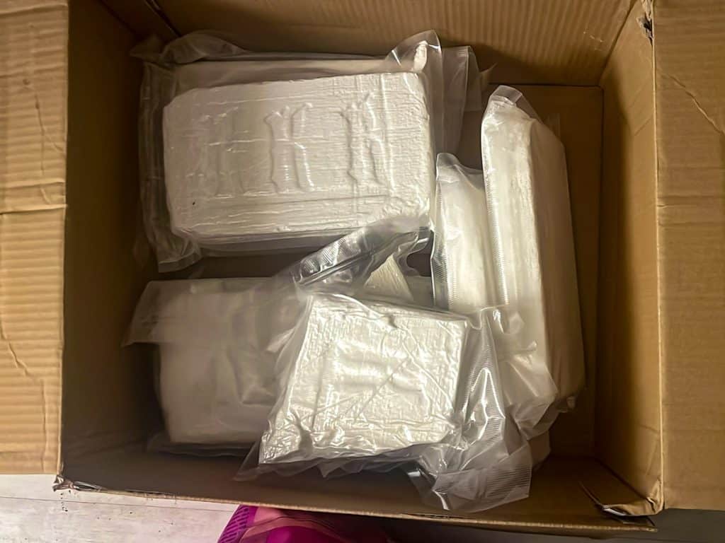 Zabezpieczone pakiety nielegalnego towaru w kartonie podczas akcji służb.