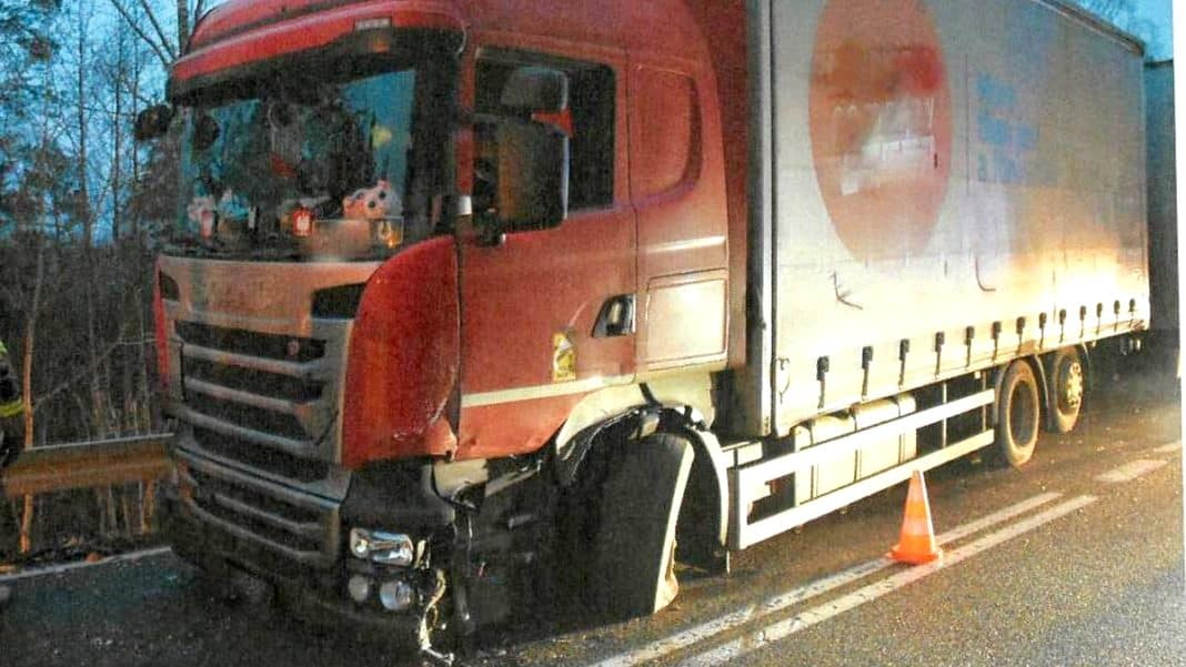 Uszkodzony ciężar&oacute;wka na drodze krajowej po zderzeniu, na miejscu stała oznakowana taśma ostrzegawcza.