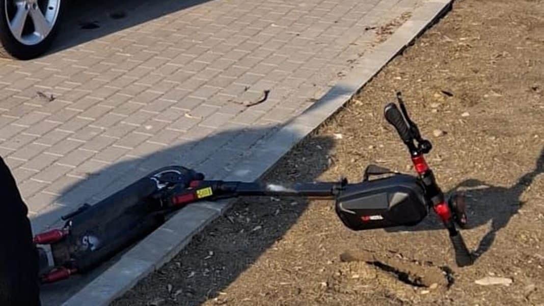 Złamana hulajnoga elektryczna na poboczu po kolizji na ścieżce rowerowej.