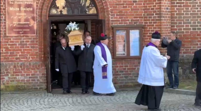 Uczestnicy uroczystości pogrzebowych Eleonory Protas w Lidzbarku Warmińskim, w tym duchowni i bliscy, wychodzą z kościoła.