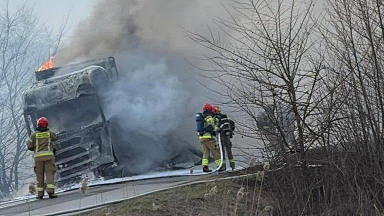 Strażacy gaszą pożar ciężar&oacute;wki na drodze w Elblągu, w tle dym i płomienie.