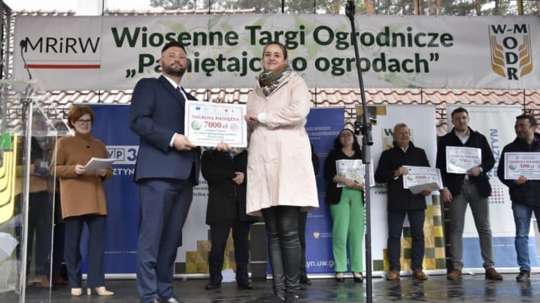Uczestnicy na scenie podczas targ&oacute;w ogrodniczych w Olsztynie, wręczanie nagr&oacute;d i prezentacja wydarzenia.