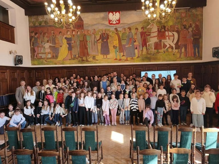 Grupa uczni&oacute;w i mieszkańc&oacute;w na oficjalnym podsumowaniu akcji sprzątania Olsztyna w ratuszu.