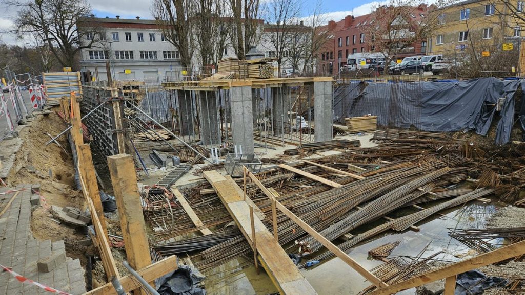 Budowa nowego obiektu hotelowo-gastronomicznego w centrum Olsztyna, widoczne prace ziemne i zbrojenia.