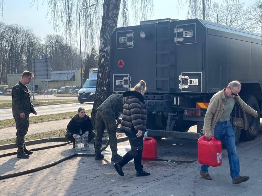 Wojsko i mieszkańcy w akcji, rozlewają wodę z cystern w regionie skażonym wodą.