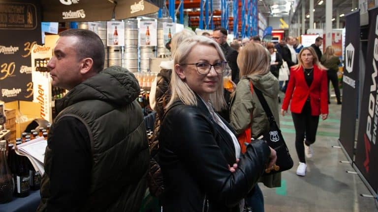 Tłum uczestnik&oacute;w na targach biznesowych w hali, stoiska z produktami i rozmowy biznesowe.