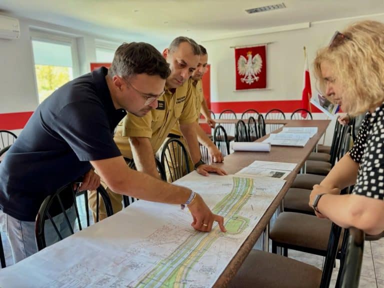 Grupa os&oacute;b omawia plany budowy nowej siedziby straży pożarnej w sali konferencyjnej.
