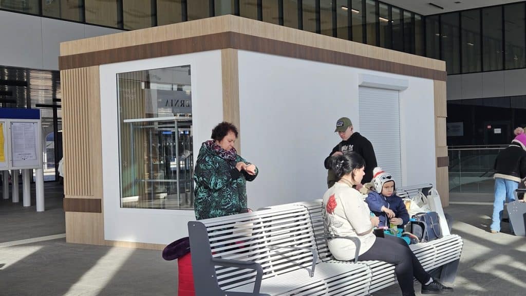 Nowa wyspa handlowa w holu dworca Olsztyn Gł&oacute;wny, z ludźmi siedzącymi na ławkach i korzystającymi z usług.