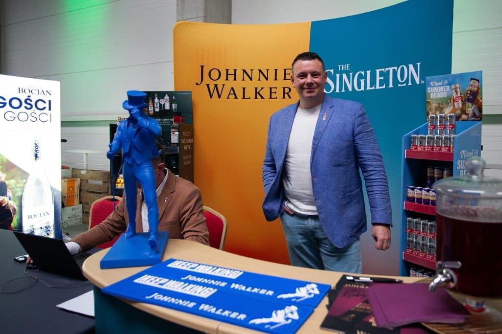 Uczestnik targ&oacute;w biznesowych w Gdańsku przy stoisku z napojami i brandingiem marki Johnnie Walker.