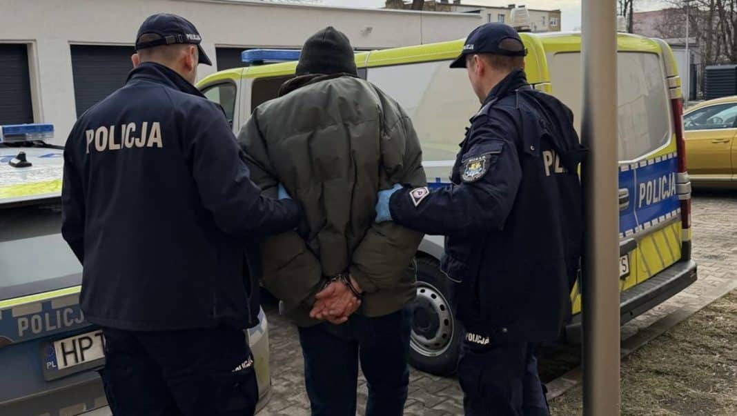 Policjanci zatrzymują poszukiwanego mężczyznę przy radiowozie na ulicy.