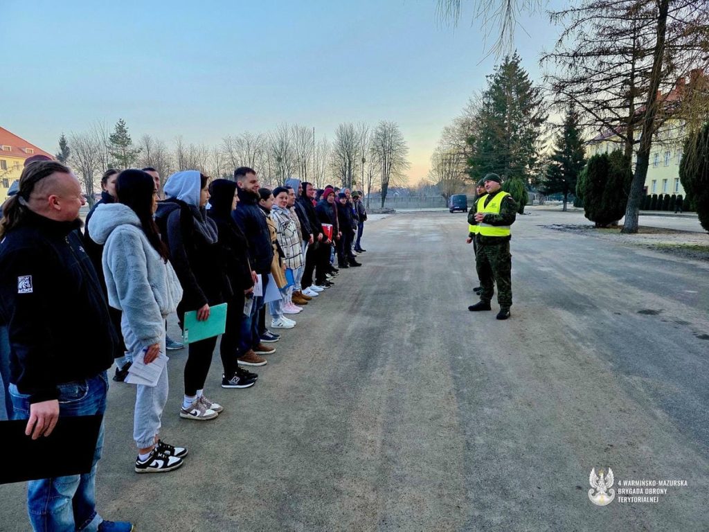 Grupa ochotnik&oacute;w słucha instrukcji w koszarach na Warmii i Mazurach.