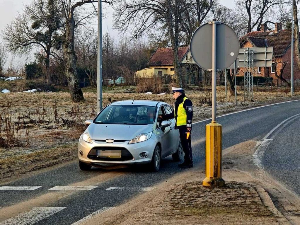Policjant sprawdza dokumenty kierowcy na bocznej drodze na Warmii i Mazurach.